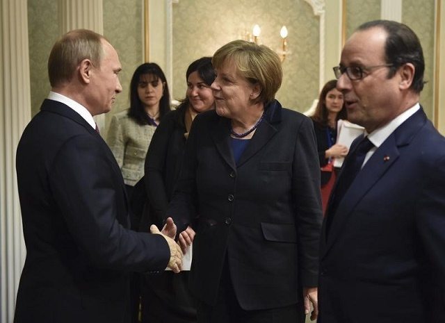 Il presidente russo Vladimir Putin (a sinistra) stringe la mano al cancelliere tedesco Angela Merkel, a destra il presidente francese Francois Hollande
